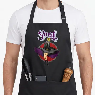Tablier de cuisine noir avec illustration d'un personnage en tenue religieuse et masque blanc sous un logo gothique violet.