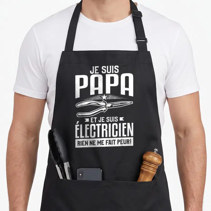 Tablier de cuisine noir avec une illustration de pince et le texte blanc Je suis papa et je suis electricien rien ne me fait peur.