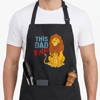 Tablier de cuisine noir avec Simba, Mufasa et l'inscription This Dad Rules en bleu et rouge.