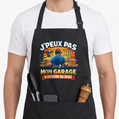 Tablier de cuisine noir avec illustration d'un homme bricolant et le message J'peux pas mon garage a besoin de moi.