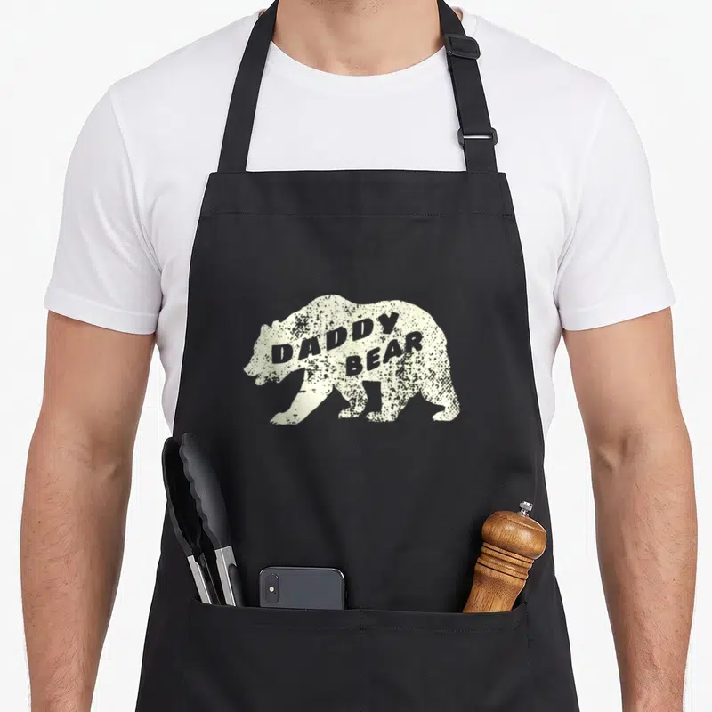Tablier de cuisine noir avec silhouette d'ours beige et texte « DADDY BEAR » en typographie usée.