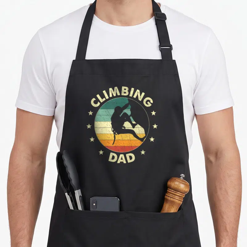 Tablier de cuisine noir avec illustration vintage Climbing Dad et silhouette d'escaladeur entourée d'étoiles.
