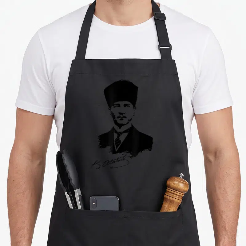 Tablier de cuisine noir avec portrait stylisé en noir et blanc de Mustafa Kemal Atatürk et sa signature K. Atatürk en bas.
