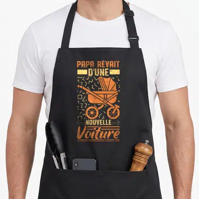Tablier de cuisine noir avec une illustration orange d'une poussette vintage et du texte « Papa rêvait d'une nouvelle voiture ».