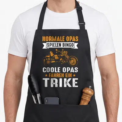 Tablier de cuisine noir avec illustration de trike orange et texte Normale Opas Spielen Bingo Trike en blanc et orange.