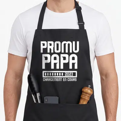 Tablier de cuisine noir avec l'inscription Promu Papa 2023 et une barre de chargement blanche.