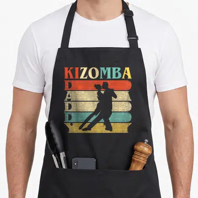 Tablier de cuisine noir avec inscription Kizomba Daddy et silhouette de couple dansant sur bandes colorées.