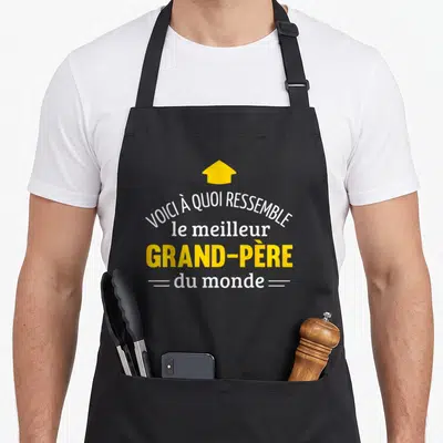 Tablier de cuisine noir avec inscription Voici à quoi ressemble le meilleur grand-père du monde et une flèche jaune.