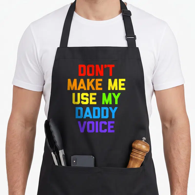 Tablier de cuisine noir avec inscription Don't Make Me Use My Daddy Voice en lettres multicolores rainbow.