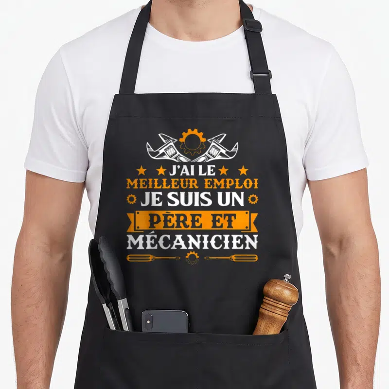 Tablier de cuisine noir avec inscription J'ai le meilleur emploi je suis un père et mécanicien entouré d'outils et d'engrenages orange.