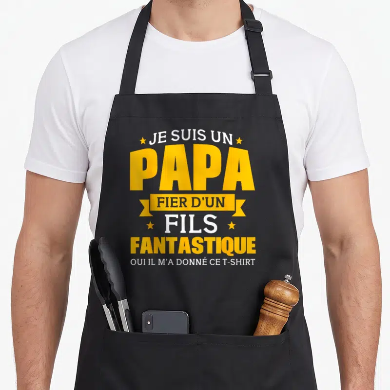 Tablier de cuisine noir avec texte jaune et blanc proclamant être un papa fier d'un fils fantastique.