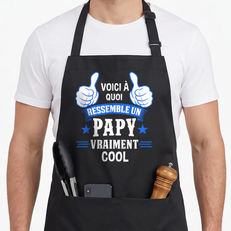 Tablier de cuisine noir avec deux pouces levés bleus et le texte voici à quoi ressemble un papy vraiment cool en blanc.