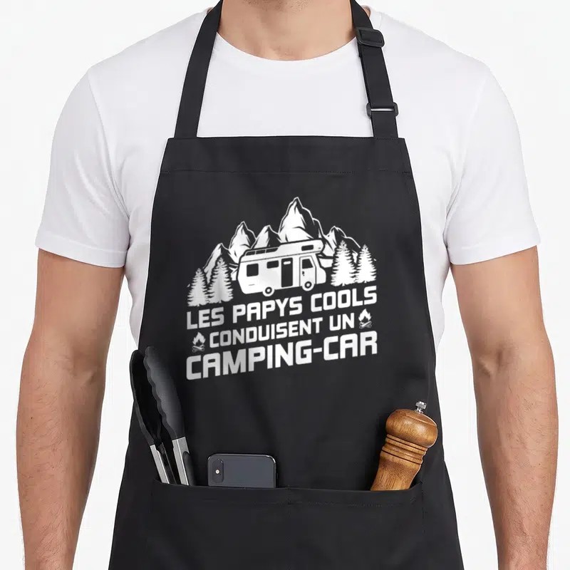 Tablier de cuisine noir avec illustration blanche d'un camping-car entre les pins et le texte Les Papys Cools Conduisent un Camping-Car.