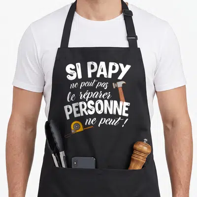 Tablier de cuisine noir avec inscription blanche et illustrations d'un marteau et d'un mètre ruban jaune.
