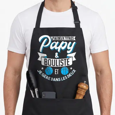 Tablier de cuisine noir avec inscription papy bouliste et pétanque illustré par deux boules bleues stylisées.
