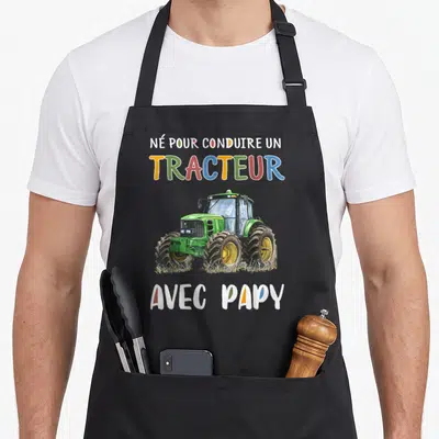 Tablier de cuisine noir avec illustration d'un tracteur vert et texte coloré né pour conduire un tracteur avec papy