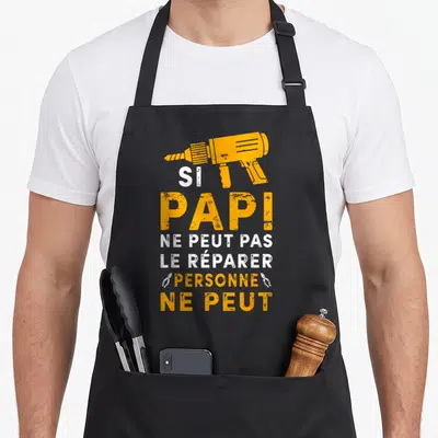 Tablier de cuisine noir avec une perceuse orange et le texte Si Papi ne peut pas le réparer personne ne peut en blanc et orange.