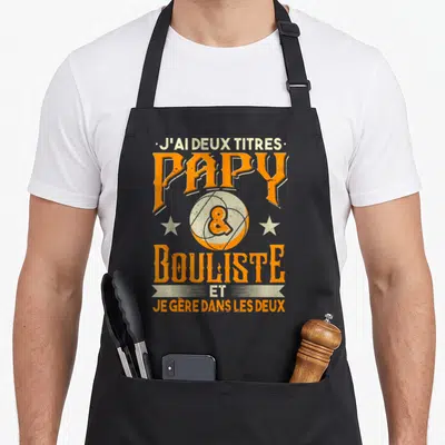 Tablier de cuisine noir avec inscription orange et crème J'ai deux titres Papy Bouliste et je gère dans les deux.