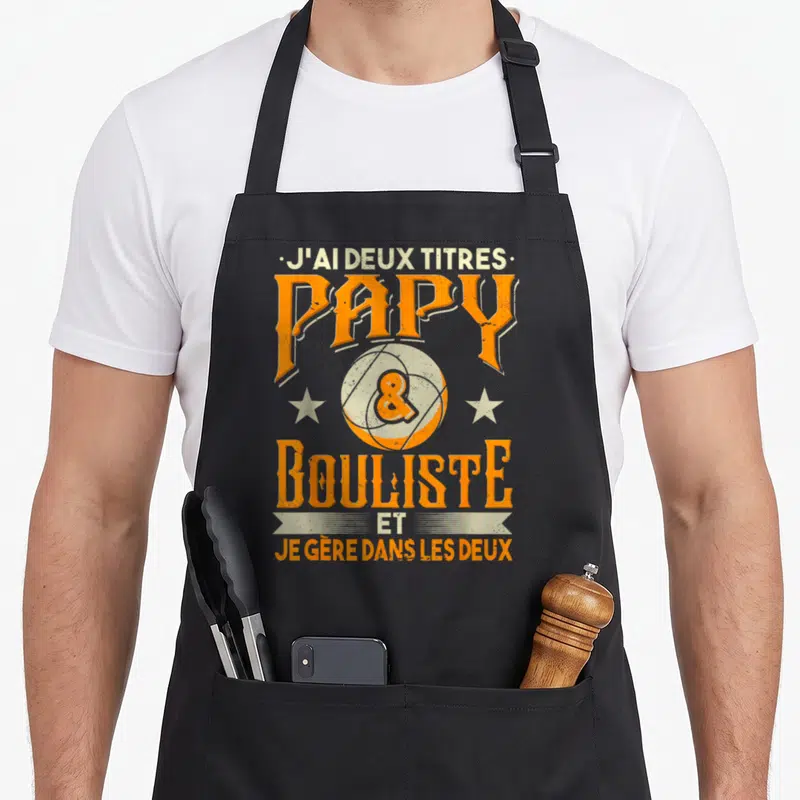 Tablier de cuisine noir avec inscription orange et crème J'ai deux titres Papy Bouliste et je gère dans les deux.
