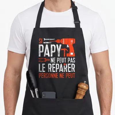 Tablier de cuisine noir avec inscription blanche et orange si papy ne peut pas le réparer personne ne peut entouré d'outils.