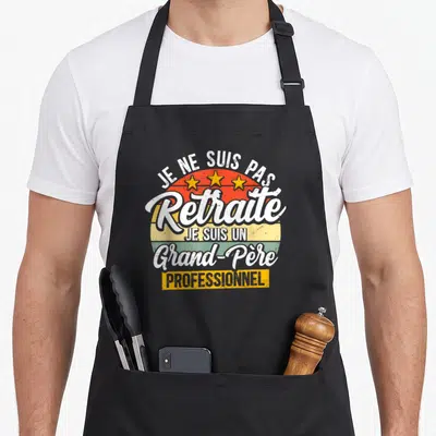 Tablier de cuisine noir avec inscription Je ne suis pas retraite grand-père professionnel et trois étoiles jaunes sur fond de soleil retro.