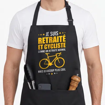 Tablier de cuisine noir avec inscription jaune et blanche Je suis retraité et cycliste illustré d'un vélo stylisé.