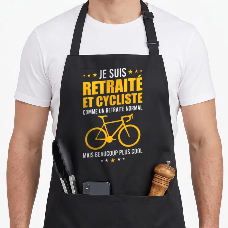 Tablier de cuisine noir avec inscription jaune et blanche Je suis retraité et cycliste illustré d'un vélo stylisé.