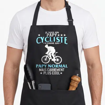 Tablier de cuisine noir avec silhouette blanche cycliste et texte bleu clair Je suis un papy cycliste comme un papy normal mais carrément plus cool