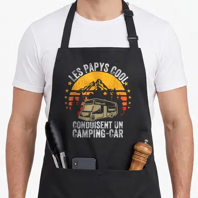 Tablier de cuisine noir avec illustration vintage d'un camping-car sous un soleil orange et le texte Les Papys Cool Conduisent un Camping-car.