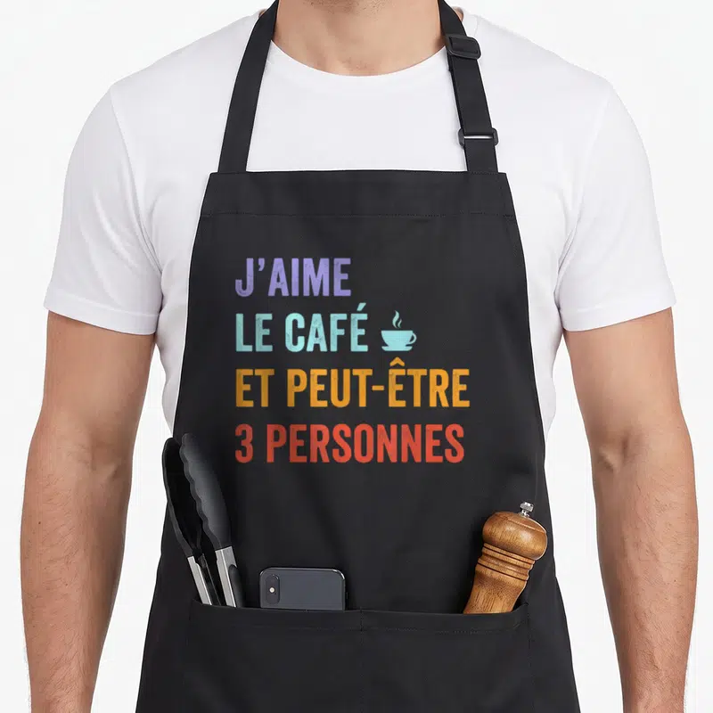 Tablier de cuisine noir avec l'inscription colorée J'aime le café et peut-être 3 personnes accompagnée d'une icône de tasse.