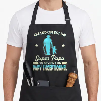 Tablier de cuisine noir avec silhouette bleue d'un homme à la canne tenant la main d'un enfant et texte blanc.