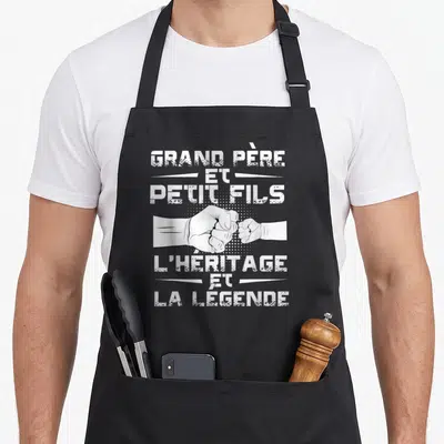 Tablier de cuisine noir avec poing d'adulte et poing d'enfant se touchant et texte blanc en typographie usée.