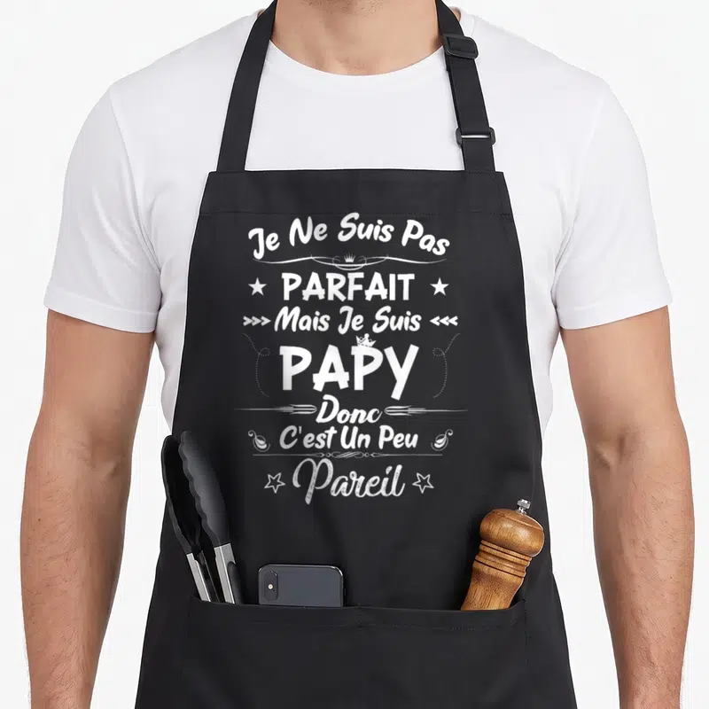 Tablier de cuisine noir avec inscription blanche Je ne suis pas parfait mais je suis papy donc c'est un peu pareil ornée d'étoiles et couronnes.