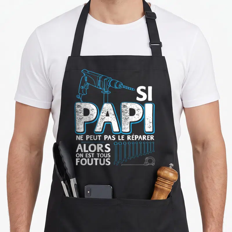 Tablier de cuisine noir avec une perceuse bleue, des clés anglaises et le texte blanc Si papi ne peut pas le réparer.