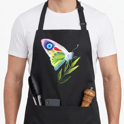 Tablier de cuisine noir avec illustration de papillon aux ailes multicolores portant un mauvais œil bleu au centre.