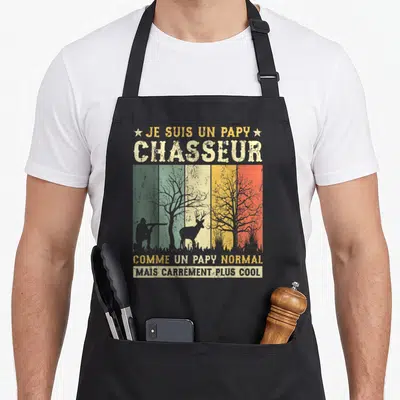 Tablier de cuisine noir avec une silhouette de chasseur, un cerf et des arbres sur fond de bandes colorées vintage.