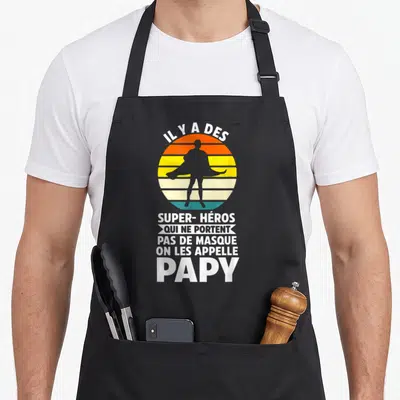 Tablier de cuisine noir avec silhouette super-héros et texte blanc Il y a des super-héros qui ne portent pas de masque on les appelle papy