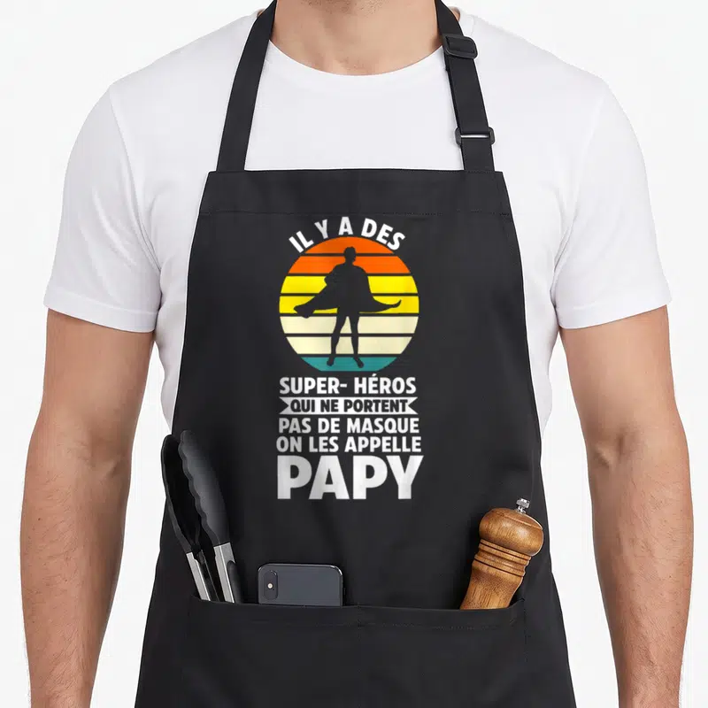 Tablier de cuisine noir avec silhouette super-héros et texte blanc Il y a des super-héros qui ne portent pas de masque on les appelle papy