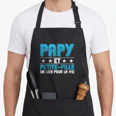 Tablier de cuisine noir avec l'inscription Papy et petite-fille un lien pour la vie en typographie bleue et blanche.