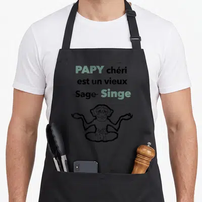 Tablier de cuisine noir avec texte Papy chéri est un vieux Singe et dessin d'un singe en position de méditation.