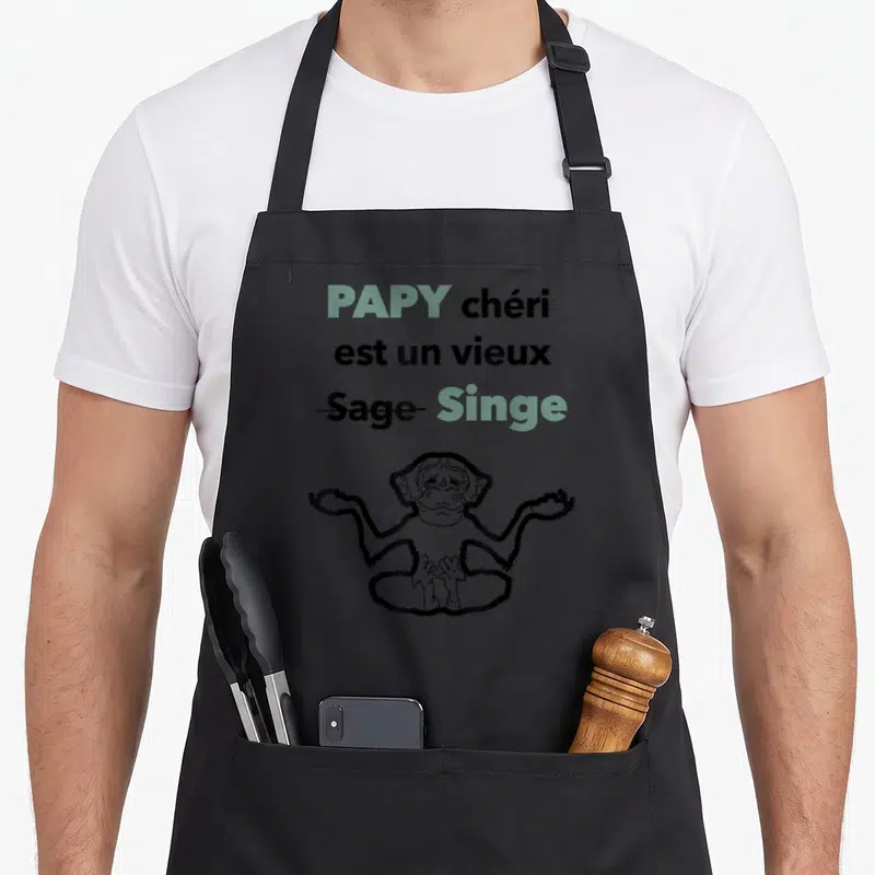 Tablier de cuisine noir avec texte Papy chéri est un vieux Singe et dessin d'un singe en position de méditation.