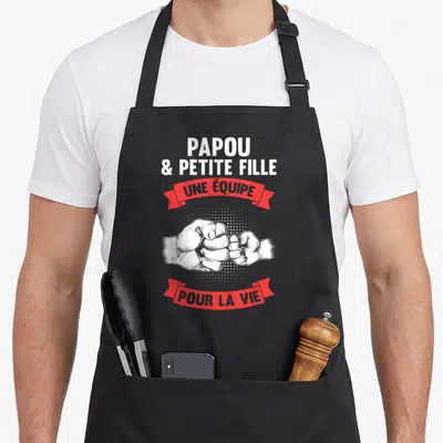 Tablier de cuisine noir avec poings se touchant et texte Papou et petite fille une équipe pour la vie en blanc et rouge.