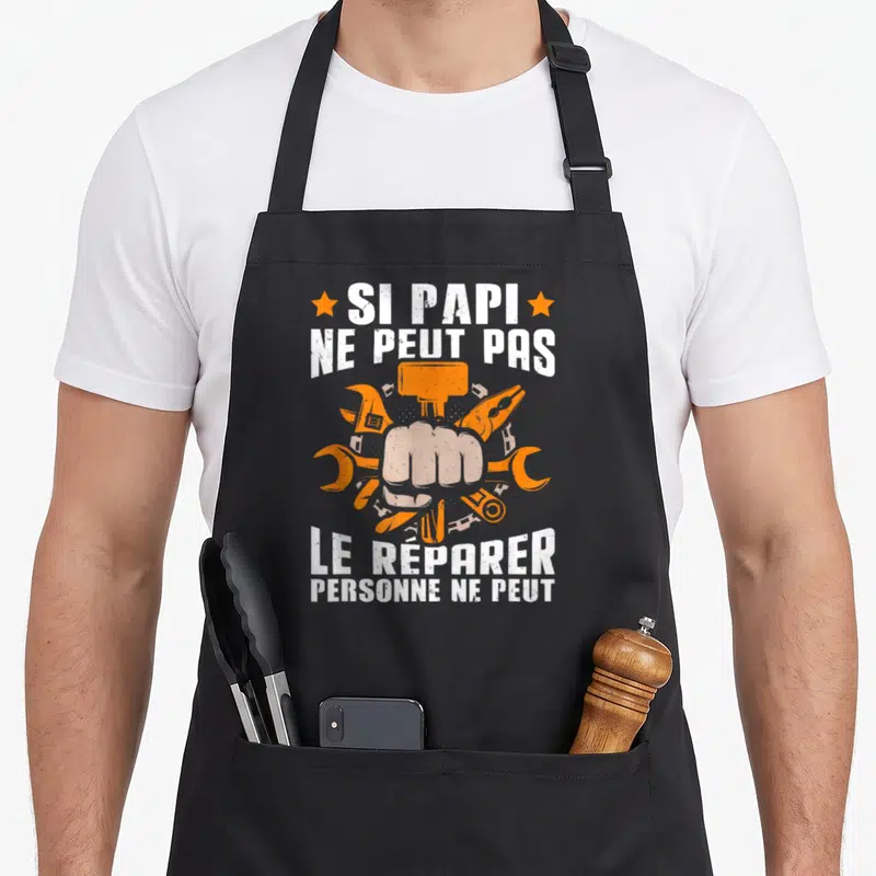 Tablier de cuisine noir avec poing et outils orange autour du texte Si Papi ne peut pas le réparer.