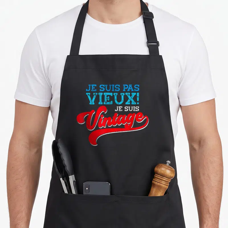 Tablier de cuisine noir avec l'inscription Je suis pas vieux je suis vintage en bleu et rouge.