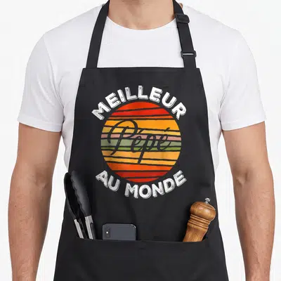 Tablier de cuisine noir avec motif rétro Meilleur Pépé Au Monde sur fond de soleil coloré.