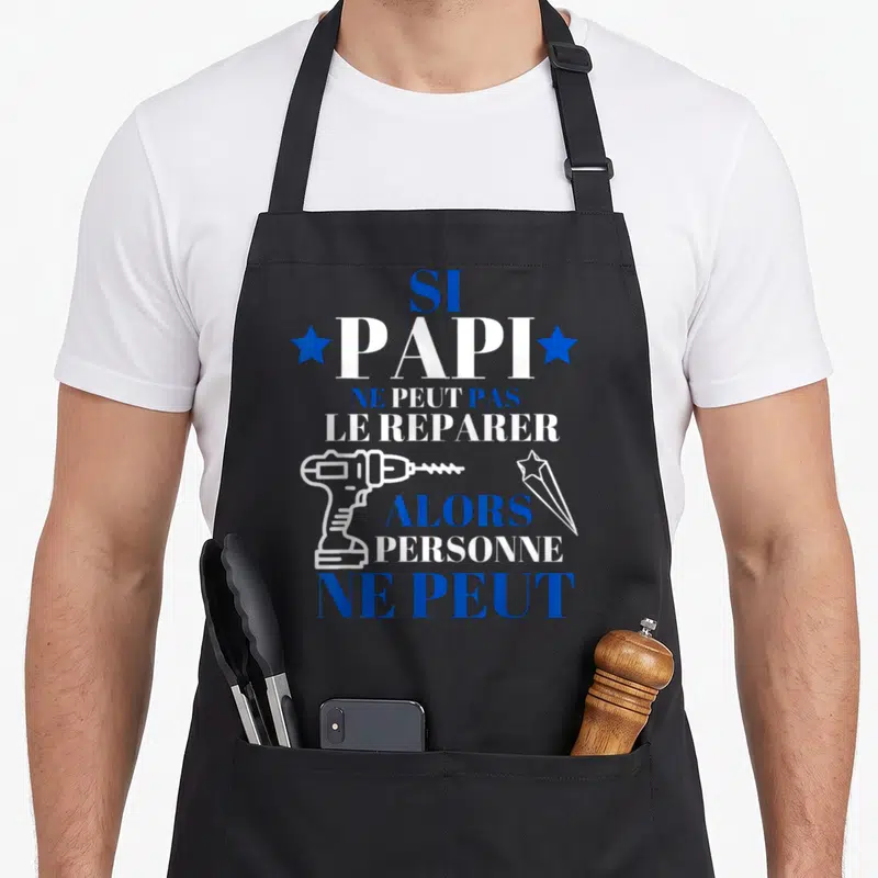 Tablier de cuisine noir avec inscription blanche et bleue Si Papi ne peut pas le réparer accompagnée d'une perceuse.