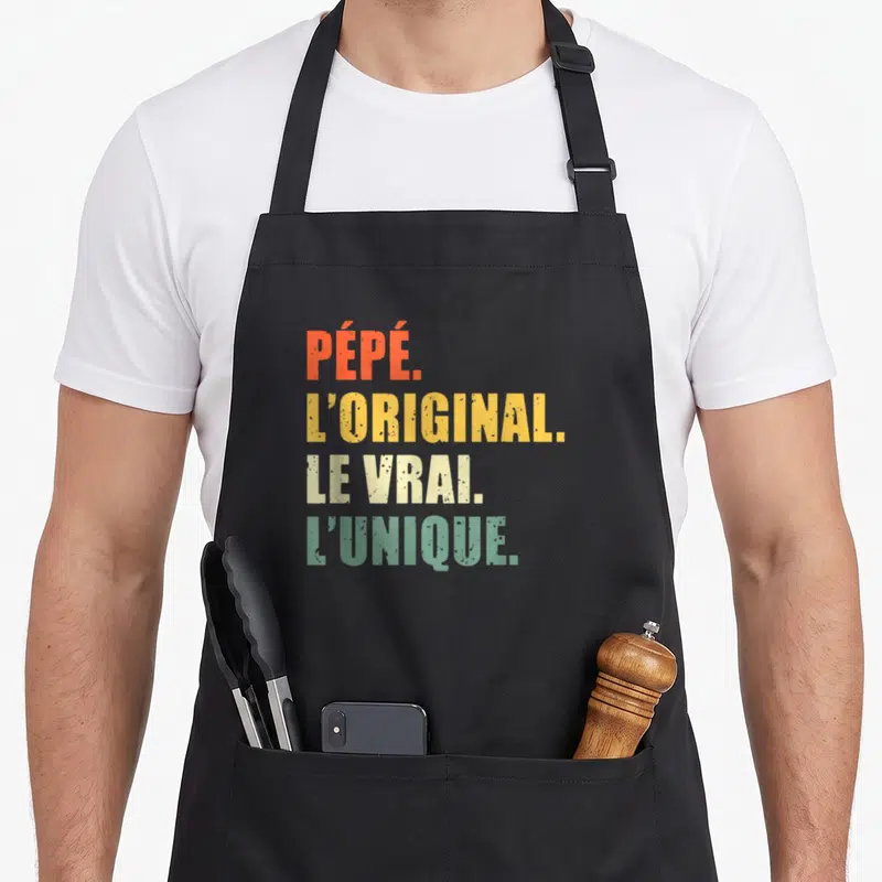 Tablier de cuisine noir avec l'inscription PÉPÉ LORIGINAL LE VRAI LUNIQUE en lettres colorées.