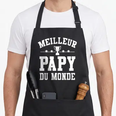 Tablier de cuisine noir avec inscription Meilleur Papy du Monde et illustration de trophée blanc au centre.