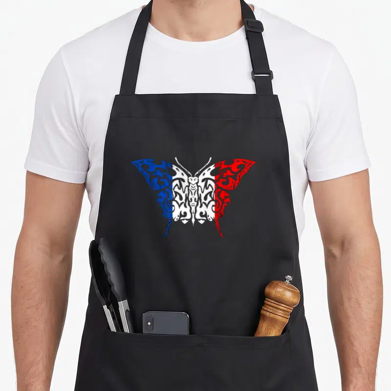 Tablier de cuisine noir avec un papillon aux ailes bleue blanche et rouge inspiré du drapeau français et de motifs tribaux.