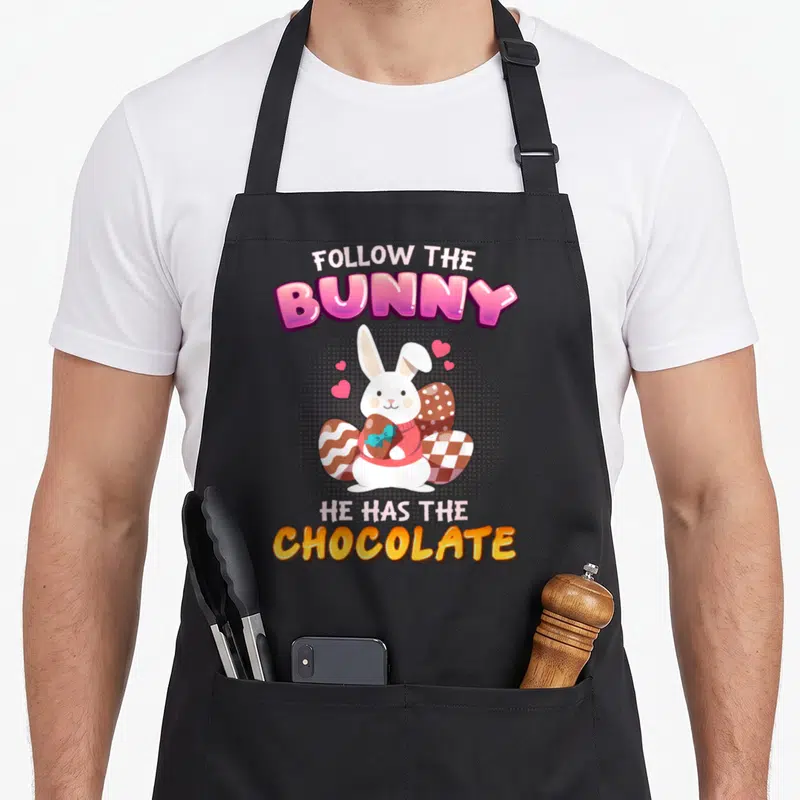 Tablier de cuisine noir avec lapin blanc tenant un œuf au chocolat et texte Follow the Bunny He has the Chocolate.
